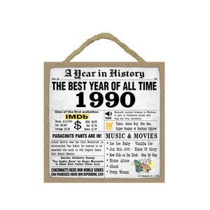 May include: A brown and beige rectangular sign with the text "A Year in History" and "The Best Year of All Time 1990". The sign lists notable events from the year 1990, including the launch of the IMDb website, the release of the movie "Pretty Woman", and the invention of the Super Soaker water gun.