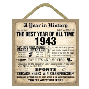 May include: A brown wooden sign with a newspaper-style design. The sign reads "A Year in History" and "The Best Year of All Time 1943". It lists historical events, including the invention of nachos, top hits and movies, and sports championships.