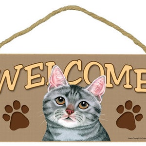 May include: A wooden welcome sign with a gray tabby cat and paw prints. The sign says "Welcome" in brown letters.