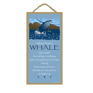 May include: A wooden sign with a blue background featuring a whale jumping out of the water. The sign has the text "Advice from a WHALE" and a list of advice: "Make a splash! Move with grace and beauty. Explore the depths of your true nature. Think big. Keep a song in your heart. Remember to come up for air. No blubbering!"