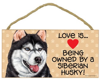 May include: A wooden sign with a black and white Siberian Husky dog illustration. The sign reads "Love is... Being owned by a Siberian Husky!" with a red heart.