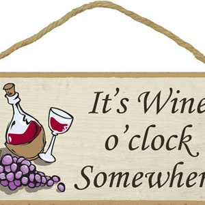 May include: A wooden sign with a rustic brown background and white text that reads "It's Wine o'clock Somewhere". The sign features a cartoon illustration of a bottle of wine, a glass of wine, and a bunch of grapes.