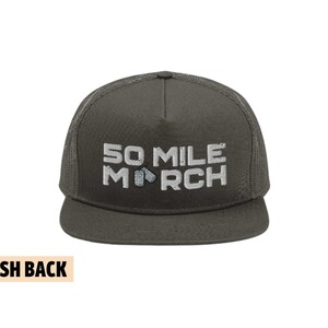 Puede incluir: Una gorra de camionero verde oscuro con una parte trasera de malla. La gorra tiene un texto bordado en blanco que dice "50 MILE MARCH" con dos pequeñas placas de identificación plateadas entre las palabras "MILE" y "MARCH".
