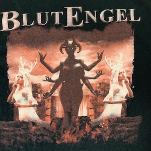 May include: Black t-shirt featuring the band name "BLUTENGEL" in white block letters above a graphic. The graphic depicts a multi-armed figure with horns, flanked by two figures with antlers, all against a fiery, orange-toned background.