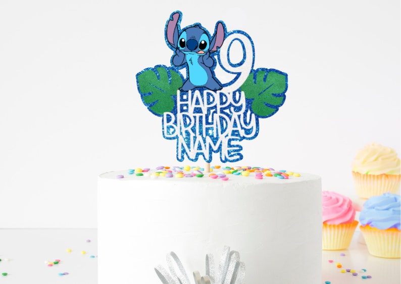 K&ouml;nnte beinhalten: Ein Tortenaufsatz mit der Figur Stitch aus Lilo & Stitch, mit der Zahl 9 und den Worten "HAPPY BIRTHDAY NAME" in blauem Glitzer. Der Aufsatz befindet sich auf einer wei&szlig;en Torte, die mit bunten Streuseln verziert ist, mit Cupcakes im Hintergrund.