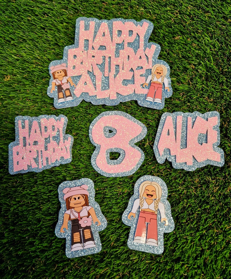 May include: Pink and blue glitter cake toppers with the words "Happy Birthday Alice" and the number "8". There are also two images of Roblox characters.