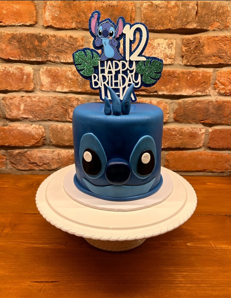 K&ouml;nnte beinhalten: Ein blauer Geburtstagskuchen mit einem Stitch-Design. Der Kuchen hat einen Aufsatz mit der Zahl 12, Stitch und den Worten "Happy Birthday Alex". Der Kuchen steht auf einer wei&szlig;en Tortenplatte.