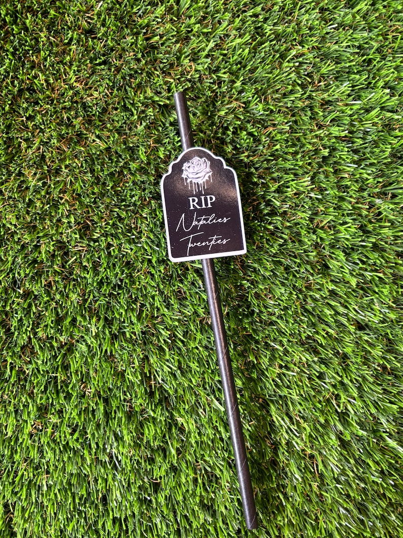 May include: Black and white tombstone-shaped straw topper with the text "RIP Napties Twenties".
