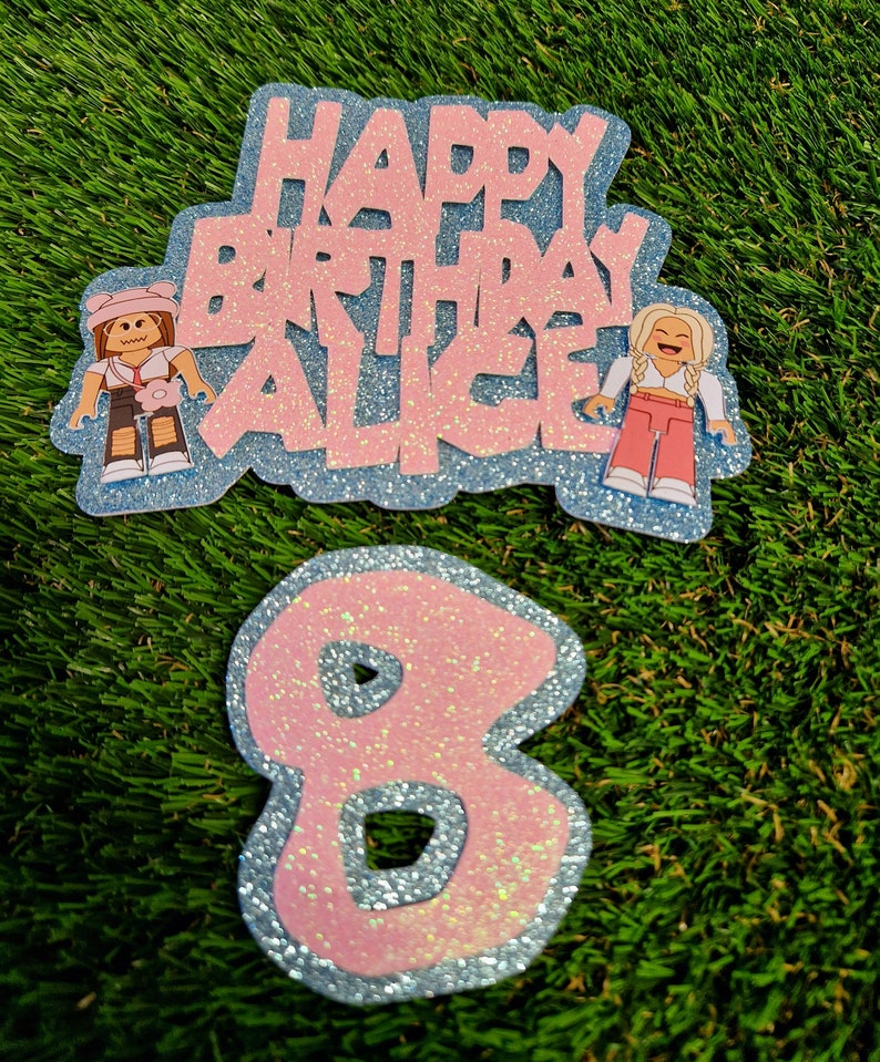May include: Pink and blue glitter cake topper with the text "Happy Birthday Alice" and two cartoon figures. A separate pink and blue glitter number 8 cake topper.