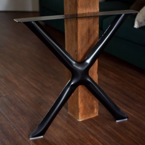 May include: Black metal table legs in an X shape, with a wooden post in the center. The legs are attached to the post with screws.