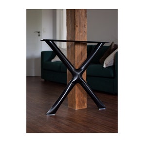 May include: Black metal table legs in an X shape with a flat top. The legs are attached to a wooden post.