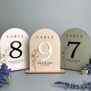 Könnte beinhalten: Ein Set aus drei Keramikbechern mit gesprenkelter, matter Oberfläche. Die Becher sind in den Farbtönen Creme, Hellgrau und Dunkelgrau gehalten. Jeder Becher hat ein schlichtes, minimalistisches Design und einen abgerundeten Henkel. Die Becher sind aufeinander gestapelt.