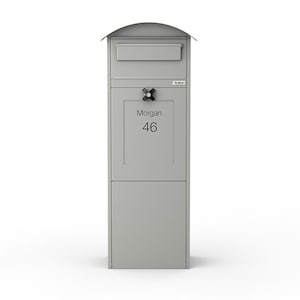 May include: A light grey, freestanding mailbox with a curved top and a lower storage compartment. The mailbox has a lock and the name "Morgan" and the number "46" printed on the front.