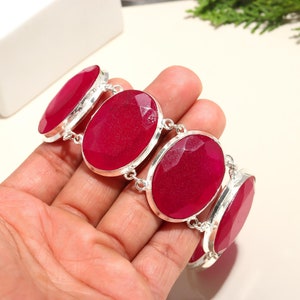 Puede incluir: Un brazalete de plata con cuatro grandes piedras preciosas rojas ovaladas facetadas. El brazalete está hecho de plata de ley y tiene un diseño elástico.