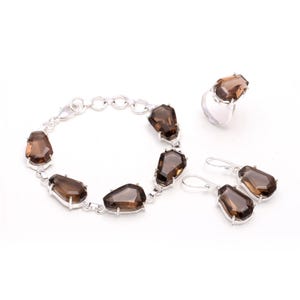 May include: A smoky quartz jewelry set with a bracelet, earrings, and a ring. The set is made of sterling silver and features faceted smoky quartz stones.