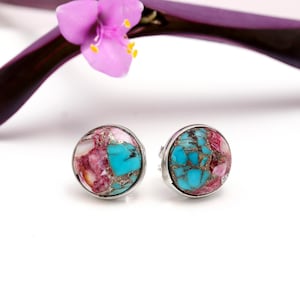 May include: A pair of silver stud earrings with turquoise and pink stone inlays. The stones are set in a round shape and have a mosaic pattern.