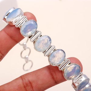 May include: A silver bracelet with oval-shaped white opal gemstones. The bracelet has a chain link closure.