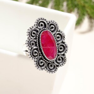 Può includere: Un anello d'argento con una grande pietra preziosa ovale di colore rosa brillante incastonata in un design a filigrana.