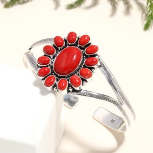 Op de afbeelding: Zilveren armband met een rood koraalbloemmotief. De armband heeft een dubbele band en een bloemmotief met een grote ovale rode koraalsteen in het midden.