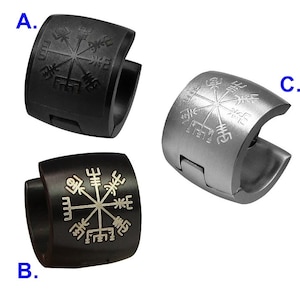 May include: Three hoop earrings with a compass design. The compass design is engraved with runes. The earrings are made of black and silver metal.