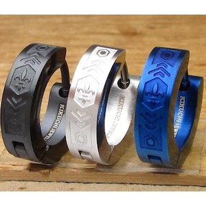 Può includere: Tre orecchini a cerchio con un design geometrico. Gli orecchini sono neri, argentati e blu. Ogni orecchino presenta un design a giglio e il testo "Kikuchi Jewel" sul lato.