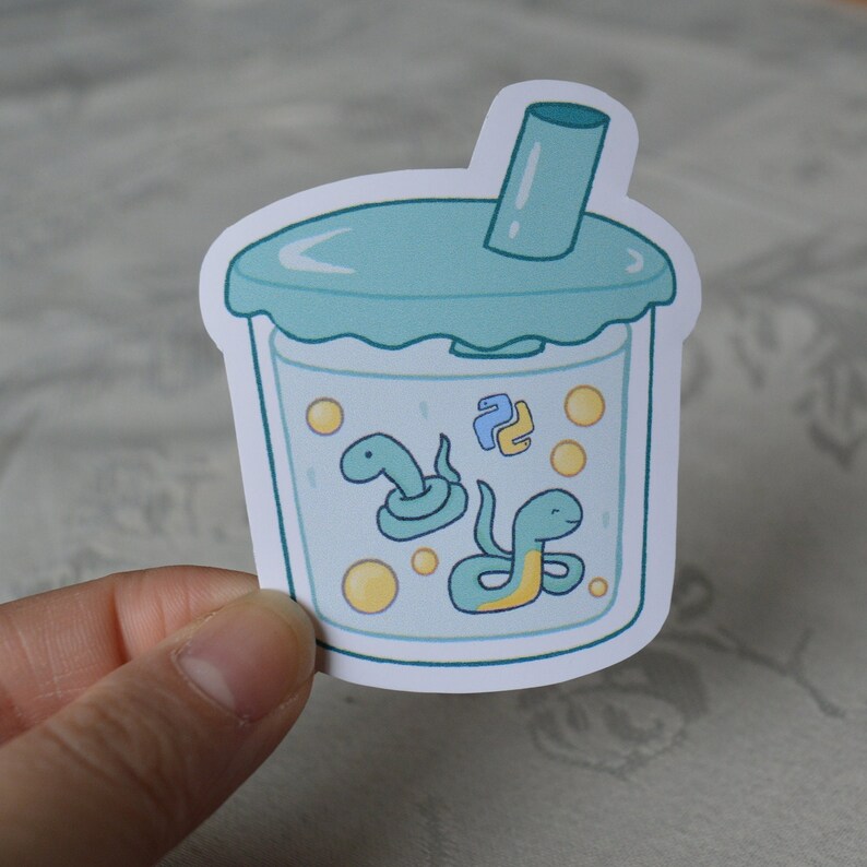 K&ouml;nnte beinhalten: Ein Aufkleber mit einem blauen und wei&szlig;en Boba-Tee-Becher mit einem Strohhalm und zwei gr&uuml;nen Schlangen darin. Die Schlangen sind zusammengerollt und haben gelbe Akzente. Der Boba-Tee-Becher enth&auml;lt gelbe Boba-Perlen.