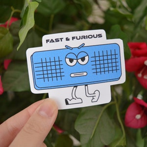 May include: A blue and white sticker with a cartoon speaker with a face. The speaker has a frown and angry eyebrows. The text "FAST & FURIOUS" is at the top of the sticker.