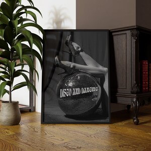 May include: A black and white photo of a disco ball with a pair of high heels resting on top. The disco ball has the text 