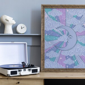 May include: A framed print with a whimsical illustration of a crescent moon with a face, surrounded by clouds and stars on a purple, pink, and green background.