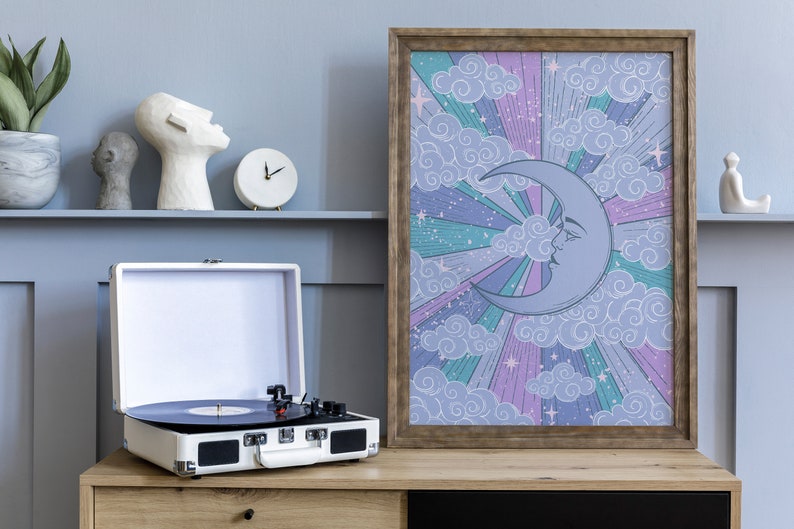 May include: A framed print with a whimsical illustration of a crescent moon with a face, surrounded by clouds and stars on a purple, pink, and green background.