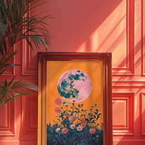 May include: A framed print of a pink and green moon rising over a field of flowers. The background is a bright orange color.