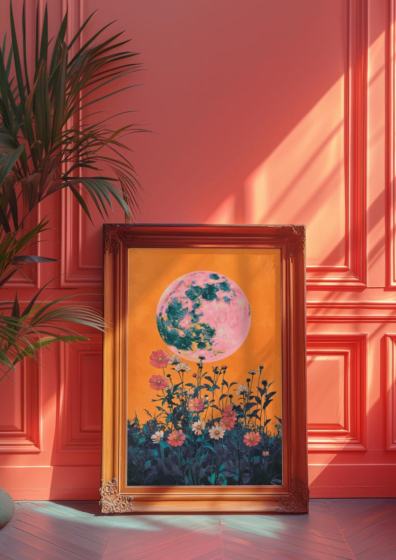 May include: A framed print of a pink and green moon rising over a field of flowers. The background is a bright orange color.
