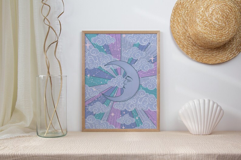 May include: A framed print of a crescent moon with a face, surrounded by clouds and stars in shades of purple, pink, and blue.