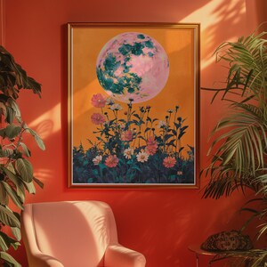 May include: A framed print of a pink and green moon with a field of flowers in front of it. The print is hanging on an orange wall.