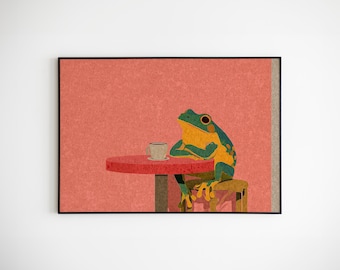 May include: A framed art print featuring a whimsical illustration of a frog sitting at a red table with a cup of coffee. The frog is green and yellow, and the background is a textured coral color.