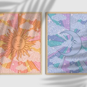 Pode incluir: Duas impressões emolduradas com um tema celestial retro. A primeira impressão apresenta um sol com um rosto e raios de luz, rodeado de nuvens e estrelas em um fundo rosa, laranja e amarelo. A segunda impressão apresenta uma lua crescente com um rosto e estrelas em um fundo azul, roxo e verde.