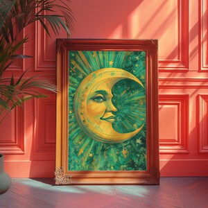 May include: A framed artwork depicting a crescent moon with a face, in yellow and green hues. The image has radiating green lines and stars, within a decorative wooden frame. The artwork is leaning against a red wall. The frame is made of wood.