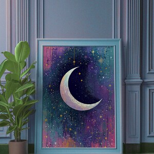 May include: A framed print of a crescent moon with a white, iridescent finish against a dark blue background with gold stars and a purple and pink nebula.