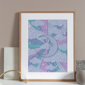 May include: A framed print with a crescent moon with a face in a purple, pink, and blue sky with clouds and stars.