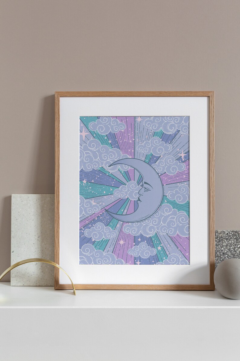 May include: A framed print with a crescent moon with a face in a purple, pink, and blue sky with clouds and stars.