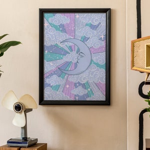 May include: A framed print with a crescent moon and clouds in a retro style. The moon is blue and the clouds are white on a purple, pink, and green background.
