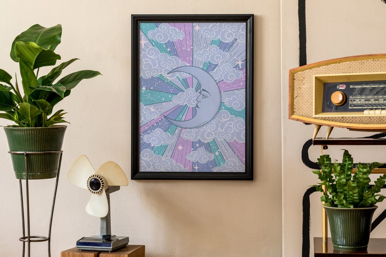 May include: A framed print with a crescent moon and clouds in a retro style. The moon is blue and the clouds are white on a purple, pink, and green background.