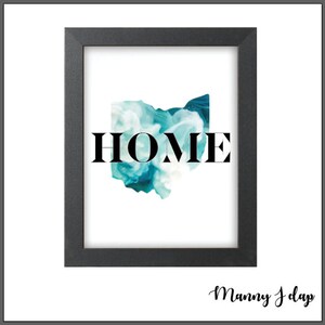 Puede incluir: Impresión artística enmarcada con la palabra "HOME" en negro sobre un diseño abstracto turquesa y blanco que recuerda a Ohio. La impresión está en un marco negro, creando una estética moderna.