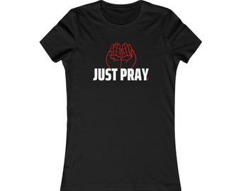 May include: Black t-shirt with the words "JUST PRAY" in white block letters. Above the text is a red outline of two hands in a praying position.