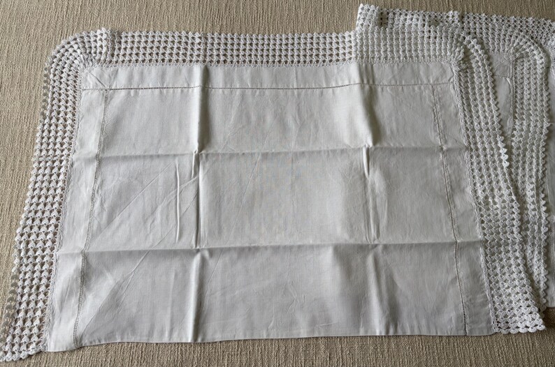 K&ouml;nnte beinhalten: Wei&szlig;e Kissenbez&uuml;ge mit geh&auml;keltem Spitzenrand. Die Kissenbez&uuml;ge sind rechteckig mit einer glatten, leicht zerknitterten Textur. Der Spitzenrand verleiht der Bettw&auml;sche eine zarte, handgefertigte Note.
