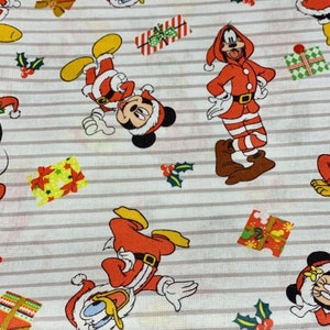 Peut inclure: Tissu blanc à rayures rouges et blanches avec un motif répété de Mickey Mouse, Donald Duck et Dingo habillés en Père Noël. Les personnages sont entourés de houx rouge et vert et de cadeaux.