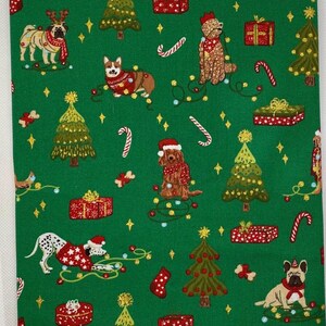 May include: Green fabric featuring a repeating Christmas-themed pattern. The design includes various dog breeds wearing festive sweaters and Santa hats, along with Christmas trees, wrapped gifts, candy canes, and twinkling lights. The fabric is likely for holiday crafts.