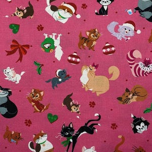 May include: Pink fabric with a repeating pattern of cats wearing Santa hats, bows, and other festive accessories. The cats are in various poses, including sitting, standing, and lying down. The background is a solid pink color.