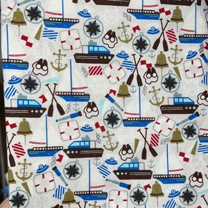 Può includere: Tessuto bianco a tema nautico con motivo ripetuto di barche blu e marroni, bussole, ancore, campane e remi. Accenti rossi e blu aggiungono colore al design. Adatto a vari progetti di artigianato.