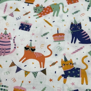 Può includere: Tessuto bianco con un motivo ripetitivo di gatti che indossano cappelli da festa e occhiali da sole. I gatti sono di vari colori, tra cui arancione, rosa, blu e verde. Lo sfondo è bianco con coriandoli e altre decorazioni per feste.